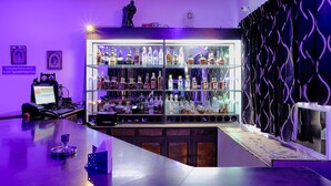 Zona de bar con una vitrina de vidrio para botellas, una computadora y un tablero de menú.