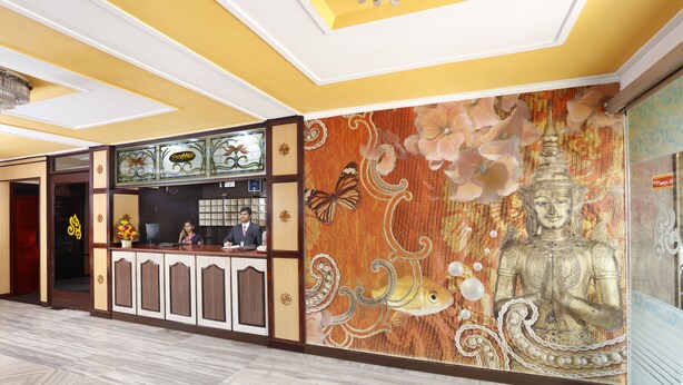Una zona de recepción con mostrador, una estatua de Buda y un mural floral.