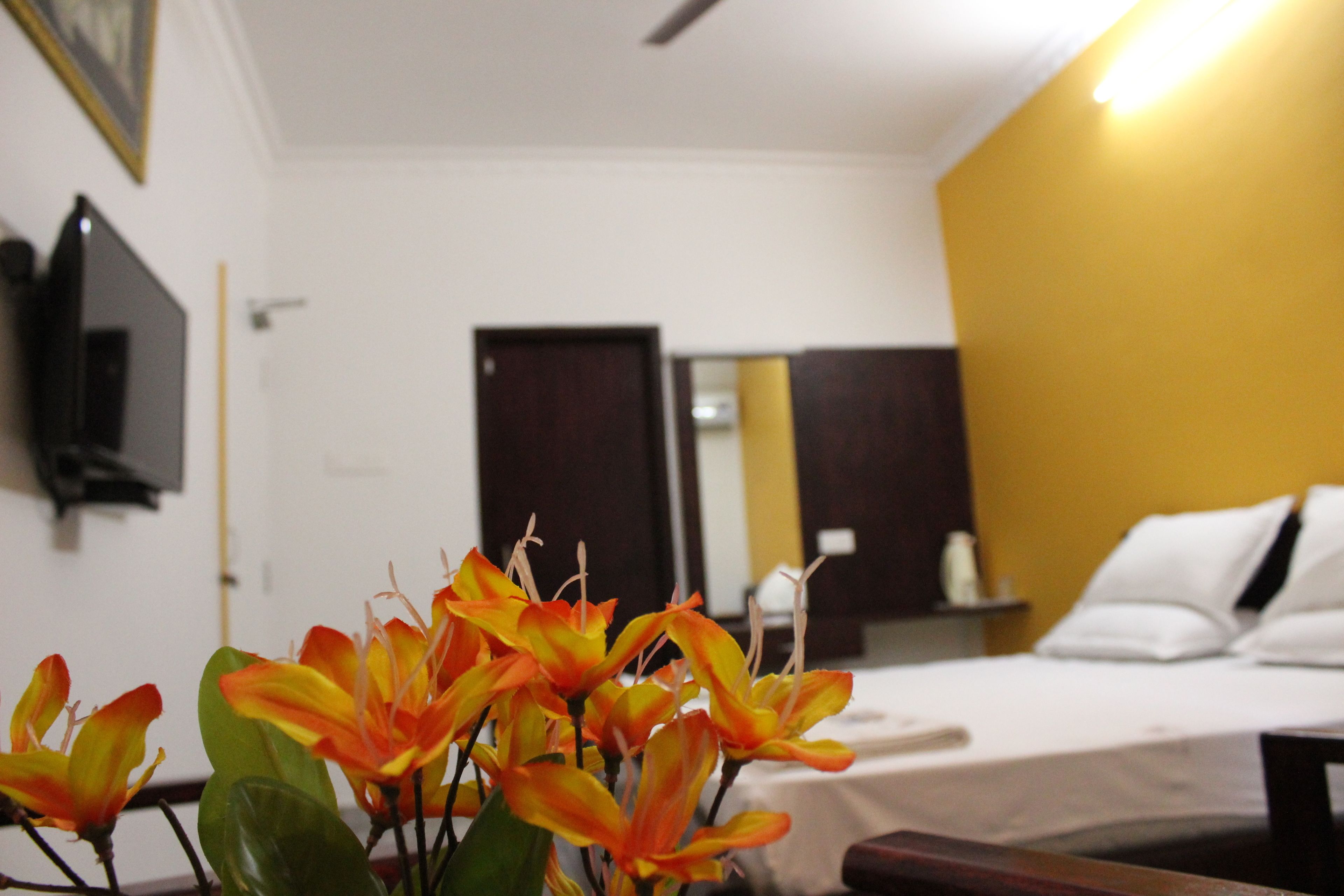 Habitación de hotel con cama, mesita de noche, espejo y televisor en la pared.