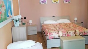 Ein Schlafzimmer mit zwei Betten, einem grünen Teppich und drei floralen Wandbildern.
