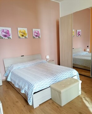 A bedroom with a bed, a nightstand, a mirror, and wall art.