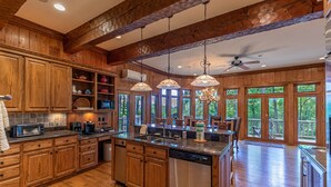 Una cocina amplia con armarios de madera, una isla grande y vistas al exterior a través de amplios ventanales.