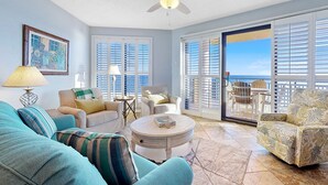 A spacious living room with a ceiling fan, large windows, and a view of the ocean. - Stunning Gulf Front Views! Sensational Amenities! (Orange Beach)