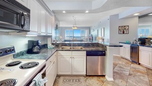 A modern kitchen with white cabinets, stainless steel appliances, and a granite countertop. - Stunning Gulf Front Views! Sensational Amenities! (Orange Beach)