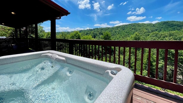 A hot tub on a wooden deck with a view of a forested mountain range. - Pet friendly 2 bedroom with hot tub, Smoky Mountain view, and arcade game! (Sevierville)