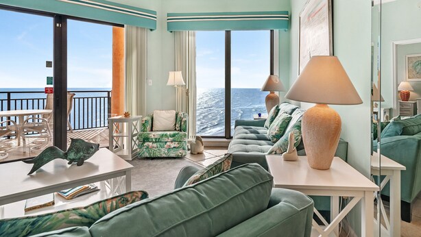 Een kamer met uitzicht op de oceaan, met een bank, een tafel en een lamp.