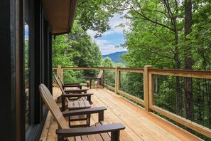 Eine Holzterrasse mit Bänken, mit Blick auf ein bewaldetes Gebiet.
