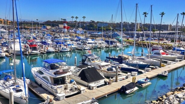 A marina with numerous boats docked, a clear sky, and a distant bridge. - 303B Perfect Location  Beach Across the Street - Walk to Shops Dining - Harbor Views (Oceanside)