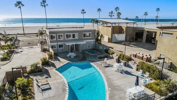 A pool area with a clear blue pool, lounge chairs, and a view of the beach and ocean.