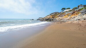 A beach with a rocky shoreline and a staircase leading to a building with a view of the ocean. - Stunning, Ocean-Front Home in Seaclift Estates in Cambria! Perfection! (Cambria)