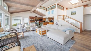 A spacious living area with a large sofa, wicker furniture, and a dining table. - Stunning, Ocean-Front Home in Seaclift Estates in Cambria! Perfection! (Cambria)