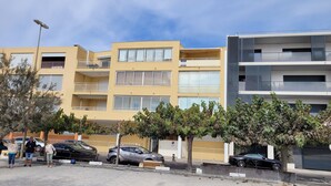 Un edificio residencial de varios pisos con balcones, una zona de estacionamiento y un farol de calle.