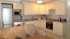 Una cocina moderna con armarios de colores claros, un microondas integrado, una estufa y un refrigerador.