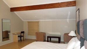Un dormitorio con una cama grande, un escritorio, una silla y una mesita.