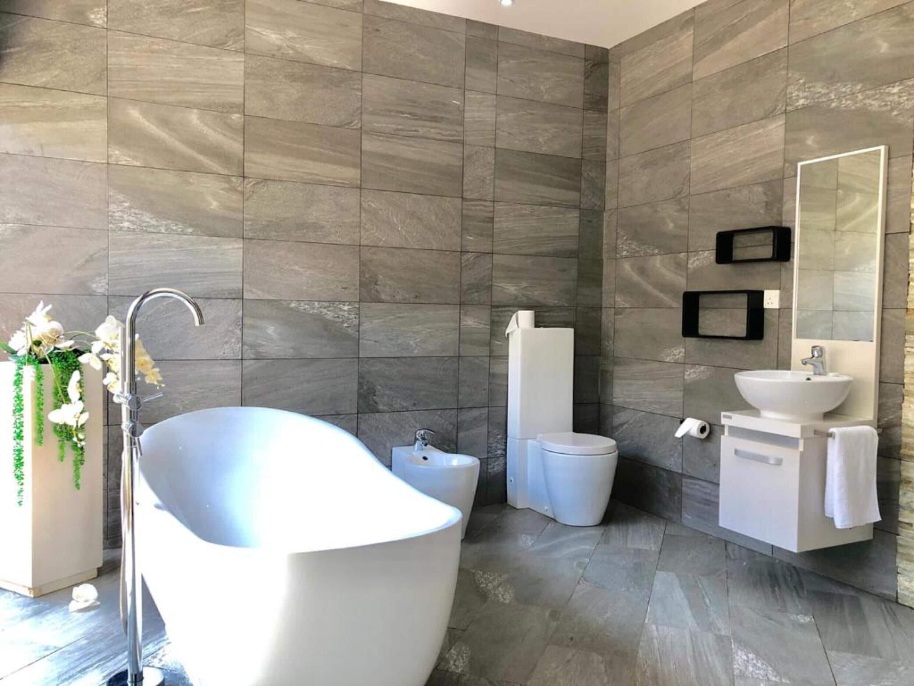 Un baño moderno con una bañera independiente, un inodoro y un lavabo con espejo.