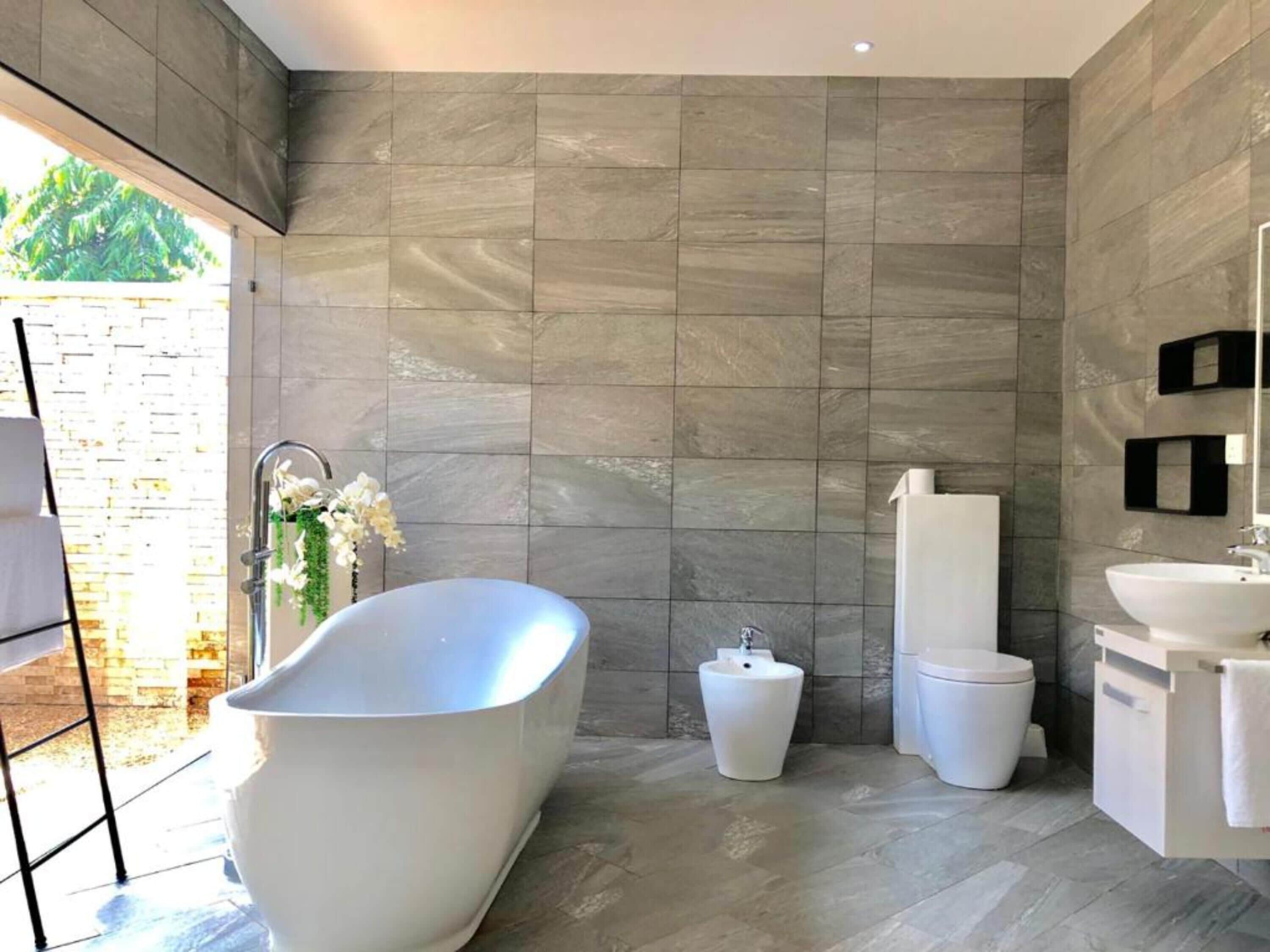 A modern bathroom with a freestanding bathtub, a pedestal sink, and a toilet.