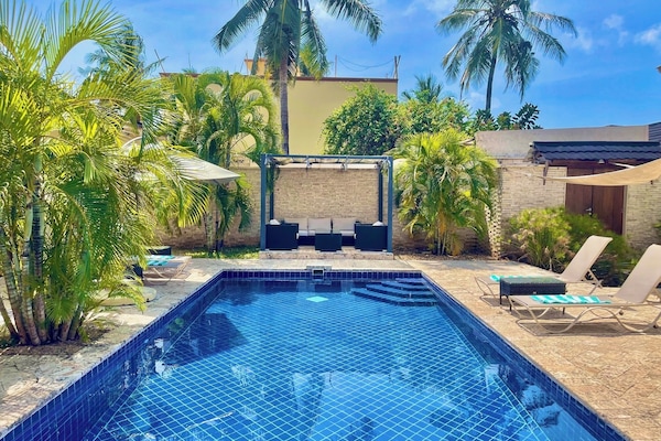 Una piscina al aire libre, sombrillas, sillones reclinables de piscina