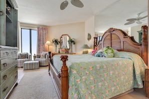 A bedroom with a large bed, a dresser, a chair, a mirror, and a ceiling fan. - Sensational Gulf Views in this Gulf Front Condo! (Orange Beach)