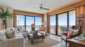 Ein geräumiges Wohnzimmer mit großem Balkon, Deckenventilator und Meerblick.
