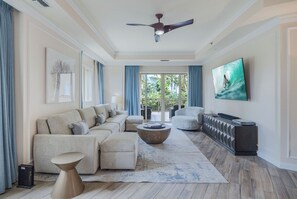 Een moderne woonkamer met een modulaire bank, een salontafel en een flatscreen televisie aan de muur.