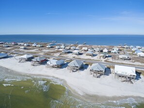 An aerial view of a coastal area with multiple beachfront houses and a road leading to the beach.