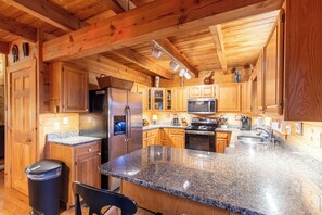 Une cuisine moderne dotée d’armoires en bois, de plans de travail en granit, d’appareils électroménagers en acier inoxydable et d’un grand îlot central.