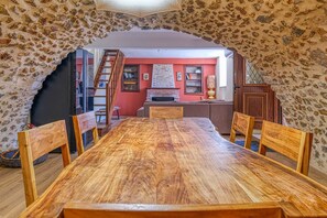 Uma sala de jantar com mesa e cadeiras de madeira, lareira e um arco de pedra.