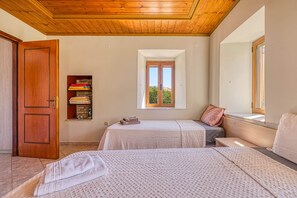 Ein Schlafzimmer mit zwei Betten, einem Holzschrank, einem Regal mit gefalteter Kleidung und einem Fenster mit Aussicht.