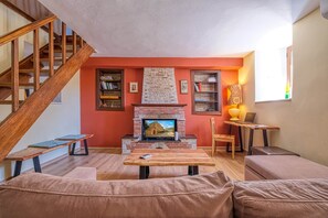 Ein Wohnzimmer mit Kamin, einer Holztreppe und einem Bücherregal.