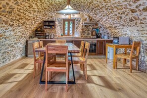 A rustic kitchen with stone walls, wooden furniture, and a central island.