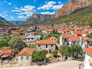 Un pueblo costero con edificios de piedra y tejados de tejas rojas, rodeado de montañas.