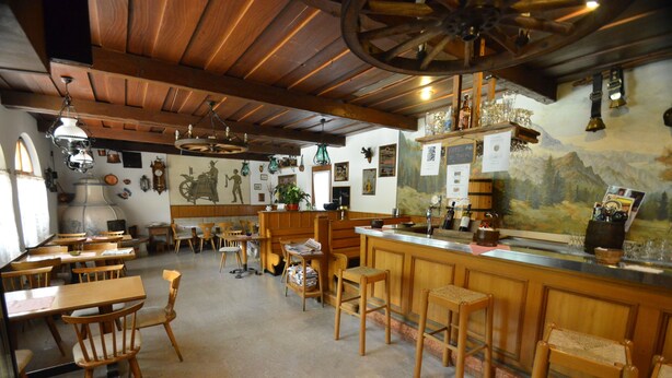 A rustic interior with wooden furniture, a bar area, and various decorations.
