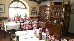 A dining area with round tables, chairs, and a wooden cabinet with glass doors.