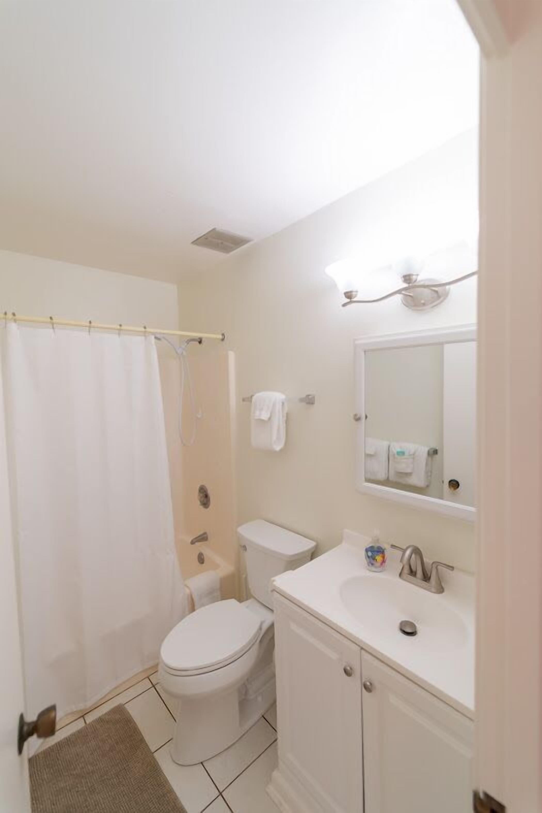 A small, clean bathroom with a toilet, sink, and shower curtain.