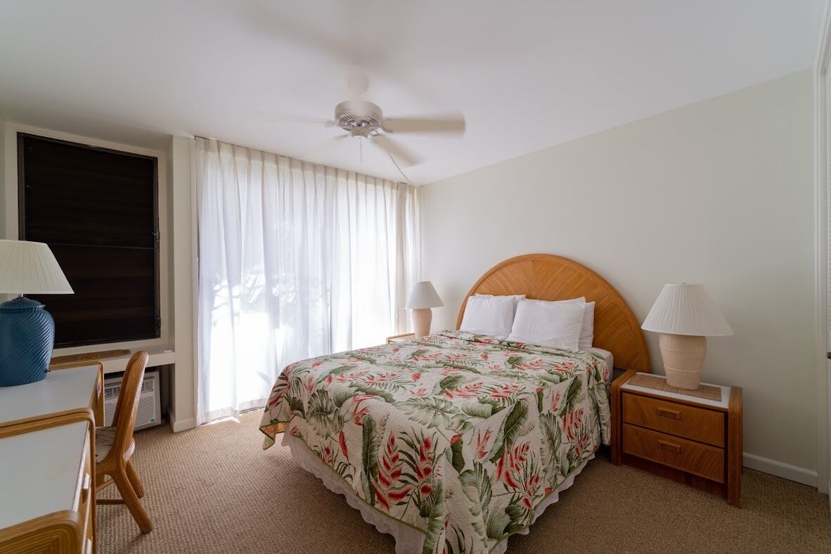Un dormitorio ordenado con cama, mesitas de noche, un escritorio y una silla.