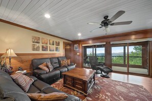 A spacious living room with a leather sofa, a wooden coffee table, and a ceiling fan.