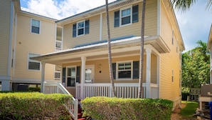 A two-story residential building with a covered porch, a small front yard, and a palm tree. - Coral Hammock Poolside Home 3 bdrm 3 bath10 minute drive to Old Town Key West (Key West)