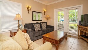 A living room with a sofa, coffee table, and a television on a wooden stand. - Coral Hammock Poolside Home 3 bdrm 3 bath10 minute drive to Old Town Key West (Key West)