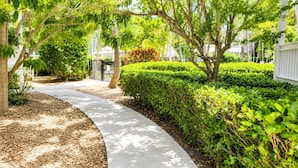 A curved pathway flanked by neatly trimmed hedges and trees, leading to a gated area. - Coral Hammock Poolside Home 3 bdrm 3 bath10 minute drive to Old Town Key West (Key West)