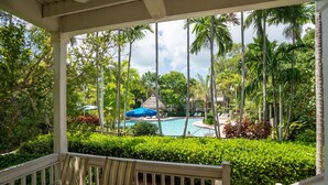 A covered outdoor area with a pool, palm trees, and a view of a resort. - Coral Hammock Poolside Home 3 bdrm 3 bath10 minute drive to Old Town Key West (Key West)
