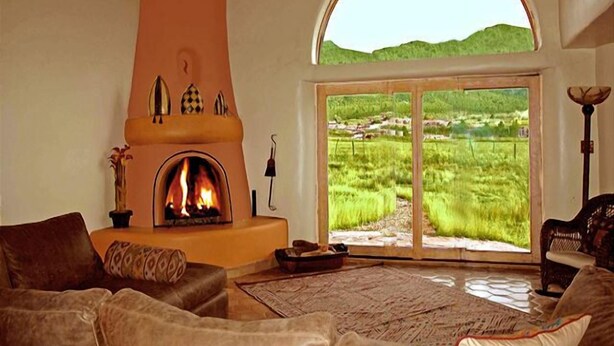 Una sala de estar con chimenea, un amplio ventanal de arco y vistas a un paisaje verde.