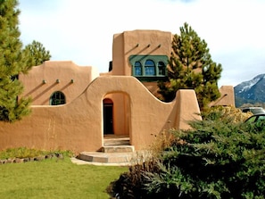 Un bâtiment recouvert d’enduit, doté d’une architecture originale, avec des fenêtres en arc de cercle et une entrée centrale.