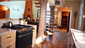Una cocina con estufa, horno y un módulo con escalera en espiral.