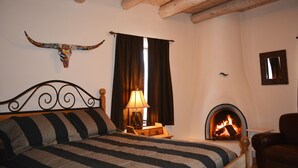 Un dormitorio con cama, chimenea, techo de madera y una cabeza de toro decorativa en la pared.