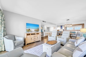 Una sala de estar moderna con un televisor de pantalla plana grande, un mueble de madera y una zona de comedor con mesa y sillas.