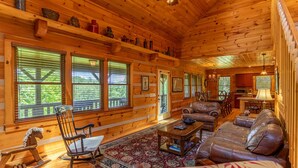 A cozy log cabin interior with a fireplace, wooden furniture, and large windows. - A Positive Outlook -10 mins to ASU, Hot Tub - Pool Table - Corner Jacuzzi (Vilas)