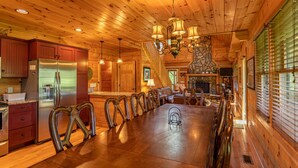 A spacious wooden cabin interior with a large dining table, built-in wooden cabinets, and a stone fireplace. - A Positive Outlook -10 mins to ASU, Hot Tub - Pool Table - Corner Jacuzzi (Vilas)