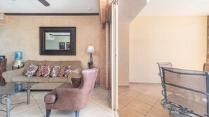 A living room with a sofa, armchair, and a glass coffee table. There is a water dispenser and a lamp on the floor.