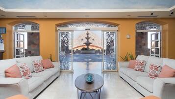 A spacious lobby with two sofas, a coffee table, and a view of a fountain through decorative glass panels.