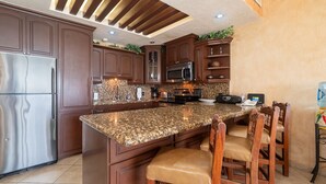 A kitchen with dark wood cabinets, granite countertops, stainless steel appliances, and a built-in microwave.